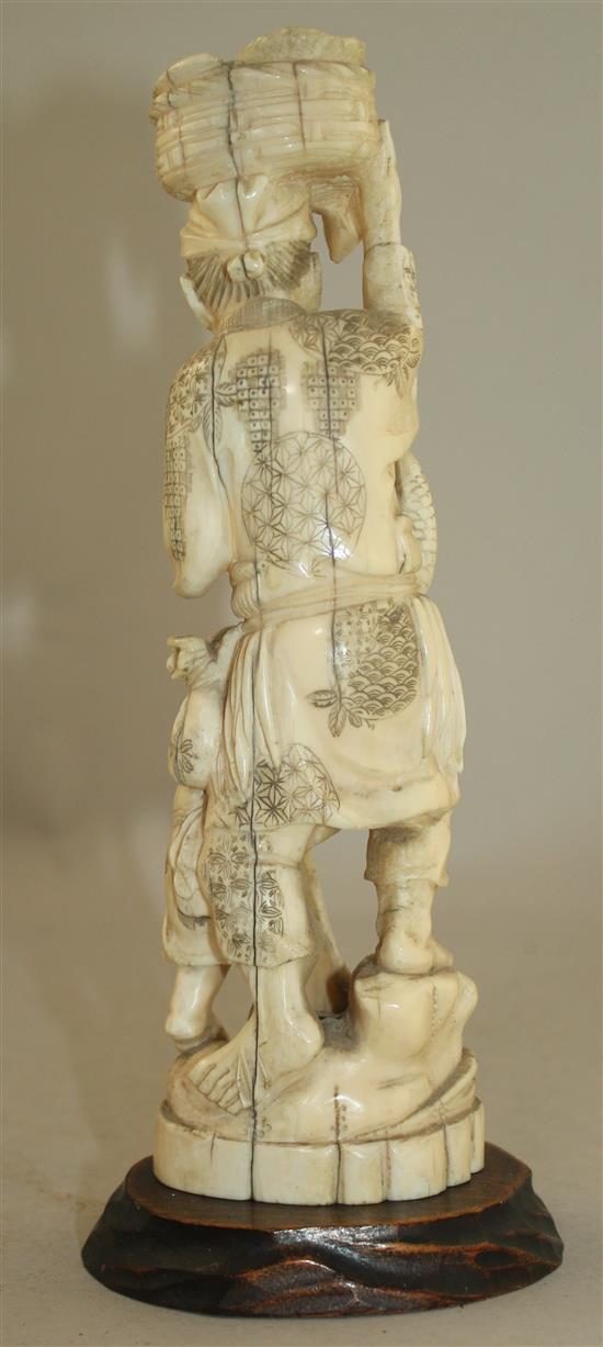 A Japanese walrus ivory group of a fisherman and a boy, early 20th century 21.5cm, wood stand